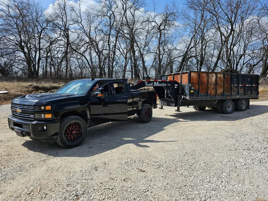 Peculiar Outdoors truck hitched to a dump trailer on a gravel pad